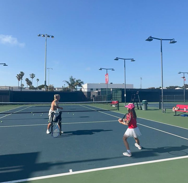 Stefania coaching a junior player on court